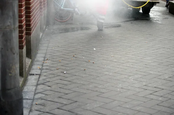 A Street cleaner clears the sidewalk in Amsterdam from dirt.