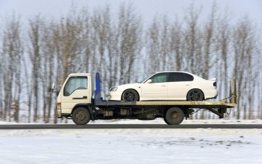 The wrecker carries the car of white color clipart