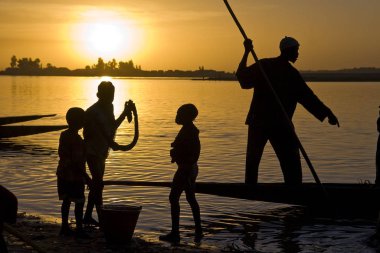 African fisherman standing in his small boat. Group of children. Africa - Mali - Mopti - Niger river clipart