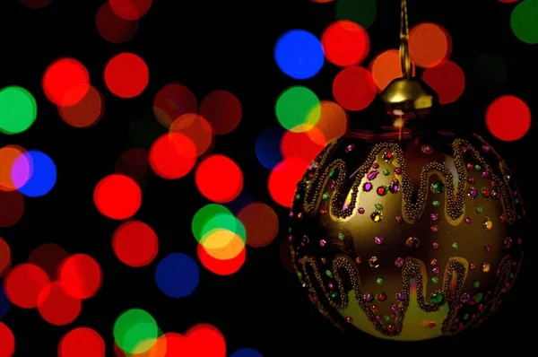 Bauble Natal Ornamentado Pendurado Contra Fundo Preto Com Luzes Coloridas — Fotografia de Stock