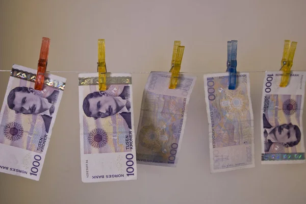 Illustration with the highest denomination of bank notes in Norway, hanging on a clothes hanger with clothes-pegs. Could illustrate money laundering and illegal business, but also a good illustration for wealth and money.