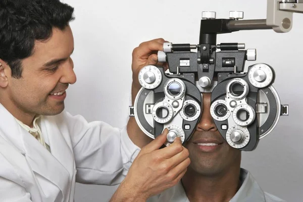 Optometrist Adjusting Panels Phoropter While Examining Patient — стоковое фото