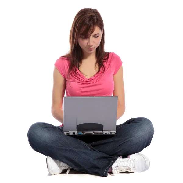 一位迷人的年轻女子在笔记本电脑上上网时 盘腿坐着 全部在白色背景上 — 图库照片