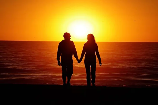 日落背景与海滩上的情侣 — 图库照片