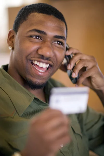 クレジットカードと携帯電話で買い物をするアフリカ系アメリカ人男性の笑顔 — ストック写真