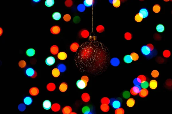 Bauble Natal Ornamentado Pendurado Contra Fundo Preto Com Luzes Coloridas — Fotografia de Stock