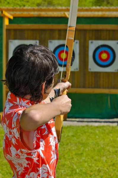 弓箭手瞄准远处目标的靶心 专注于弓箭手的头 箭只是可以看到 在焦点 在靶心 — 图库照片
