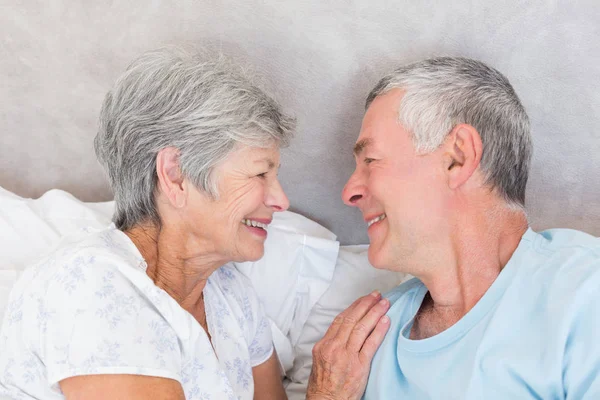 微笑的高级夫妇在床上看着对方 — 图库照片