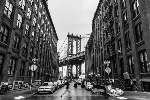 Manhattan Bridgeas seen from Washington street in Brooklyn, New York City, USA.  Motion blured jogger running in foreground. Black and white image.