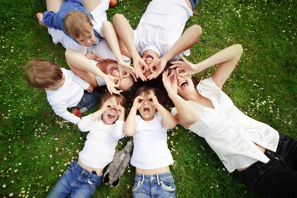 草の上に横たわって子供を持つ幸せな親のグループ — ストック写真