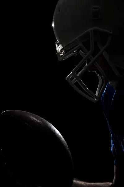 Football Player with number on a blue uniform and a ball in the hand. Studio shot.