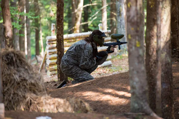 Paintball Player in Camouflage Clothing Hiding during Game