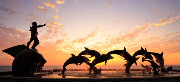 Standbeelden Van Dolfijnen Fontein Voor Fel Oranje Zonsondergang Boven Oceaan — Stockfoto