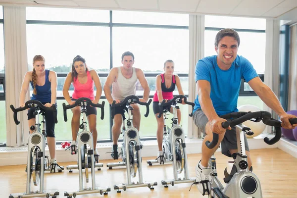 Portrait of a happy man teaches spinning class to four people at gym