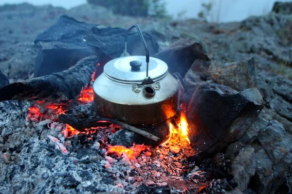 Boiling water in a kettle on a burning bonfire.