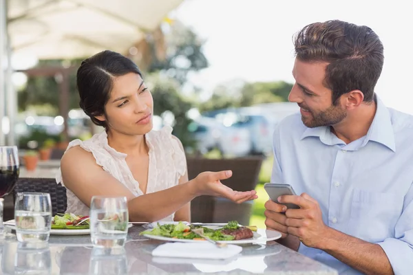 Annoyed woman taking phone from her date in patio of restaurant