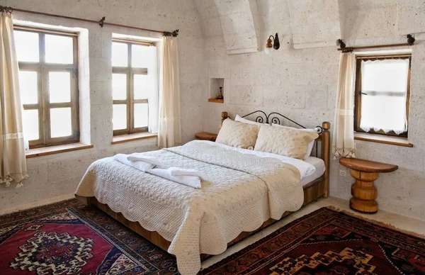 interior detailing of bedroom under the limestone arches, white detailed bedspread and cushions furniture, woven mats and net curtains. Landscape, copy space and crop area