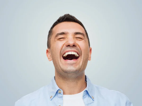 happiness, emotions and people concept - laughing man over gray background
