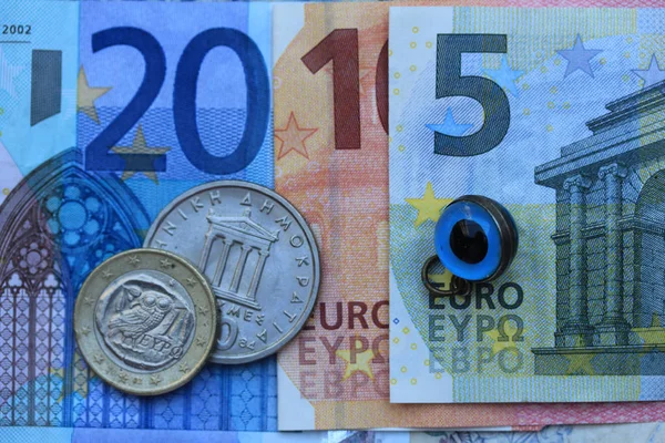 Greek Euro crisis 2015: vintage Greek Drachma coins on Euro notes and the Greek evil eye