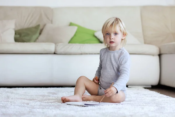 幼児の家庭でカーペットの上に座っている絵を描く — ストック写真