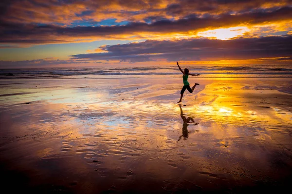 ジャンプ女性のシルエット 夕日の浜 — ストック写真