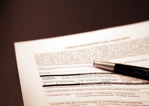 Home loan application document on black background. Black and silver ink pen resting on the financial paperwork. Document intended for home loan, mortgage loan, mortgage application, loan applicate and real estate sales.