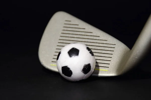 黒い背景に孤立した小さなサッカーと金属ゴルフクラブ — ストック写真