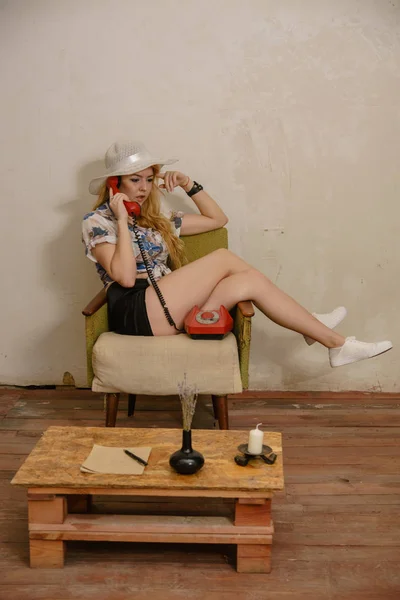 Красивая Блондинка Белой Шляпе Сидит Кресле Скрещенными Ногами Общаться Телефону — стоковое фото