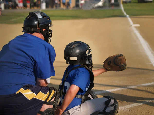 little league baseball catcher and umpire behind home plate
