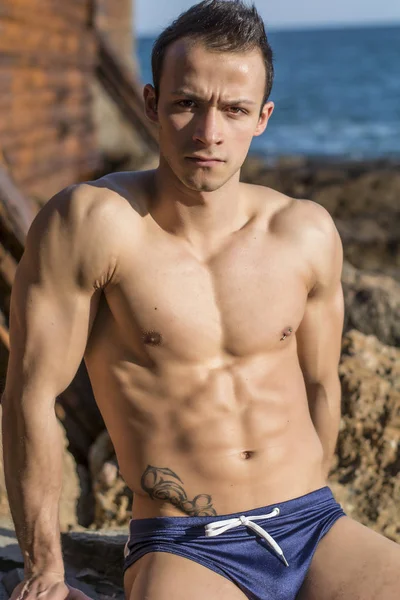 Musculoso Joven Sin Camisa Tomando Sol Roca Junto Mar Océano —  Fotos de Stock