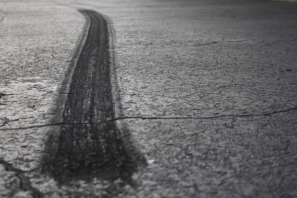 A rear tire burnout or skid mark on old cracked asphalt.