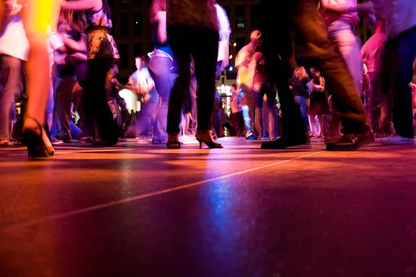 A low shot of the dance floor with people dancing under the colorful lights