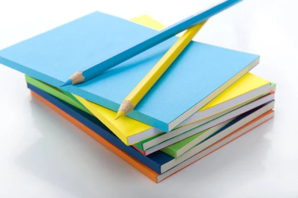 Üst Çalışma Kitabı Yığını Üzerinde Mavi Sarı Kalemlerbeyaz Arka Plan — Stok fotoğraf