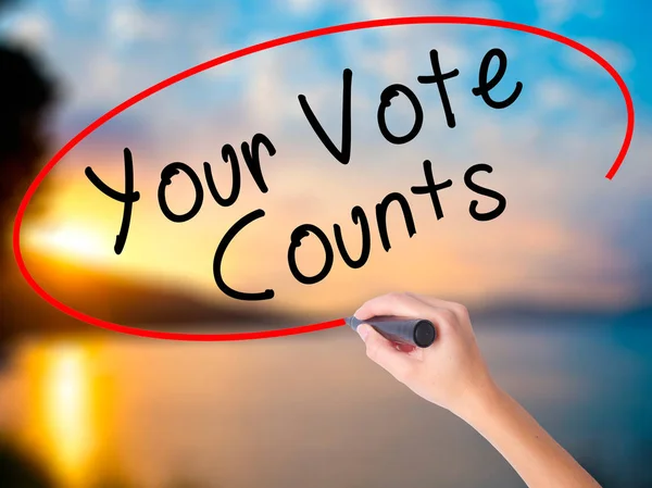 Women Hand writing Your Vote Counts with black marker on visual screen. Isolated on Sunset. Business, technology, internet concept. Stock Image