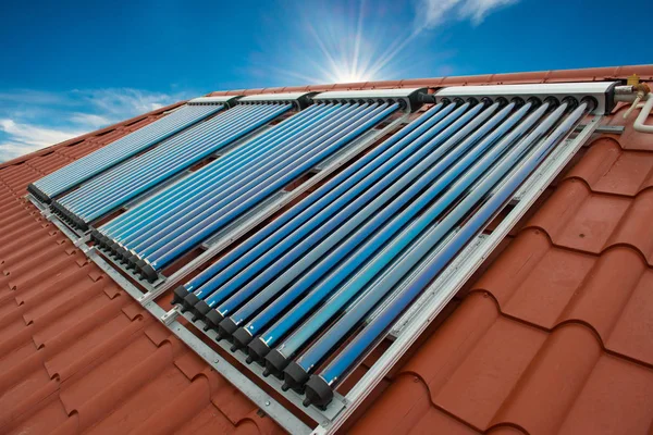 Vacuum collectors- solar water heating system on red roof of the house.