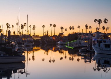 Sunset over residential development by water in Ventura California with modern homes and yachts boats clipart