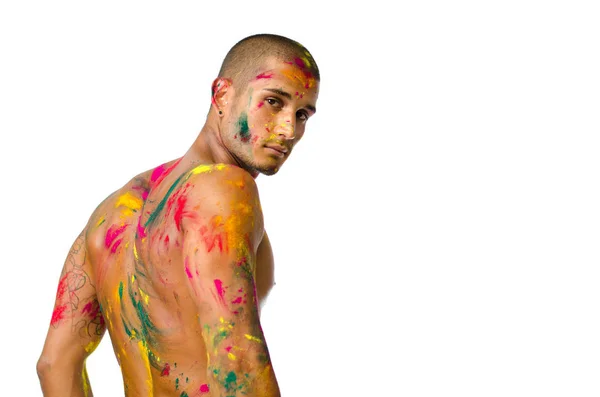 Attractive young man shirtless, skin painted all over with bright colors seen from behind