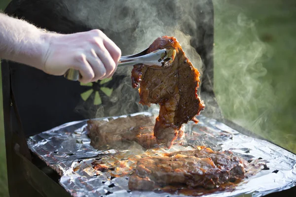 Marinated ribeye steak being turned on a grill