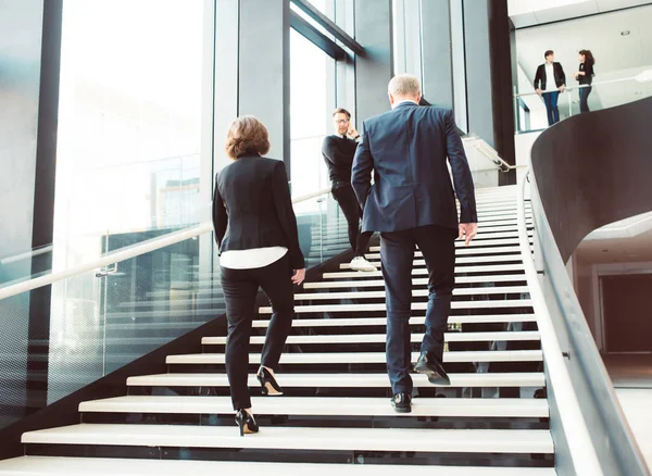 Modern business people walking on stairs in glass hall of office building