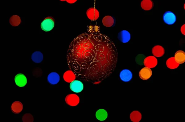 Bauble Natal Ornamentado Pendurado Contra Fundo Preto Com Luzes Coloridas — Fotografia de Stock