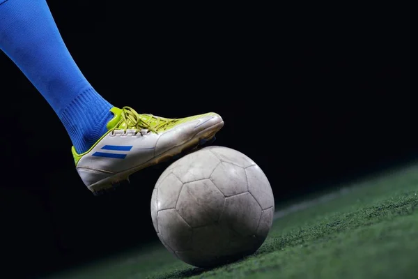 黒の背景上に分離されてサッカー スタジアムのフィールド上のボールをキックしているサッカー選手 — ストック写真