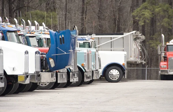A group of Tractor Trailor Trucks in a parking lot