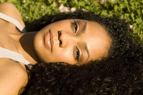 Çiçeklerle Yeşil Çimenlerde Yatan Çekici Bir Genç Siyah Kız Portresi — Stok fotoğraf