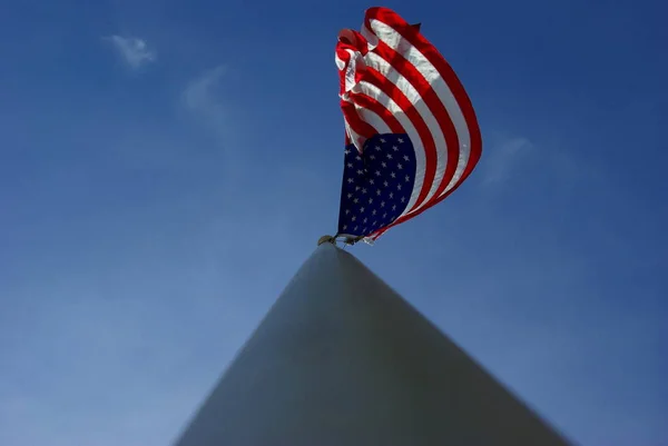 A unique view of a large American flag flying from the top of an aluminim flagpole.