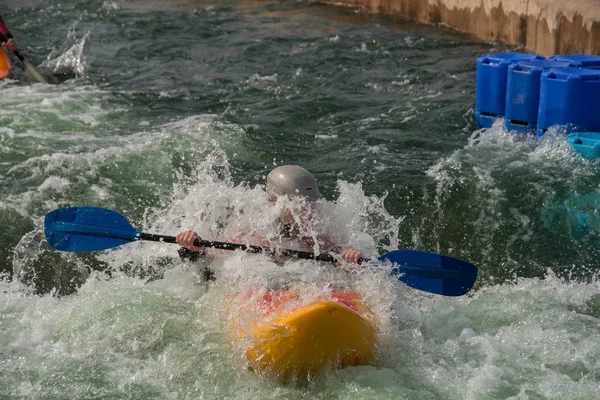 A single kayak, entering the rapids on a man made, white water course