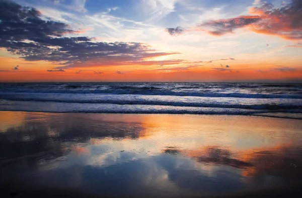 海滩上色彩斑斓 多云的落日 倒映在地平线上 — 图库照片