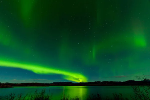 オーロラボレアリスまたはオーロラの輝く緑色の夜空ショーは ラバージュ湖の穏やかな表面に反射 ユーコン準州 カナダ — ストック写真