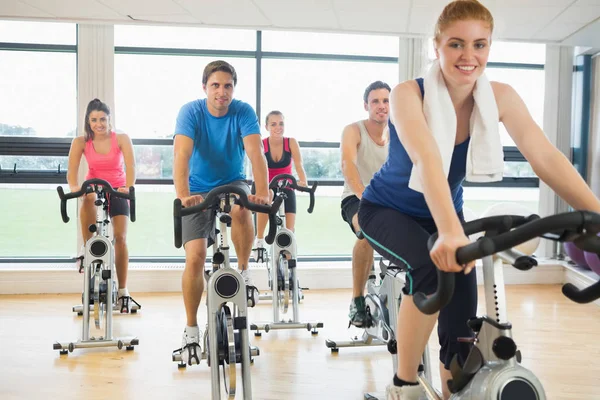 Portrait of a happy woman teaches spinning class to four people at gym