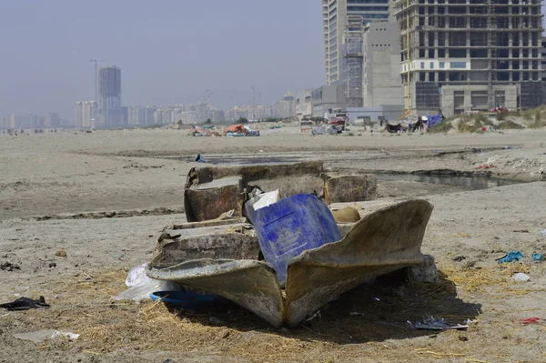 A boat washed ashore on the beach near the city.