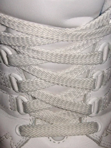 shoe-laces threaded in the eyelets of a training shoe